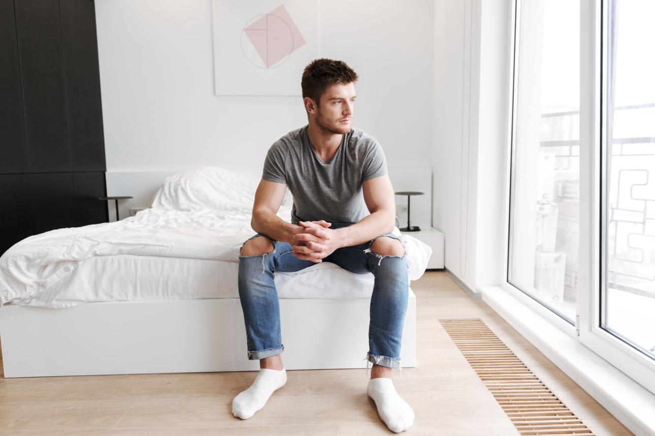 Concentrated young man sitting on his bed